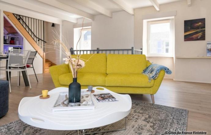 a living room with a yellow couch and a table at Le Gîte du Port in Roscoff