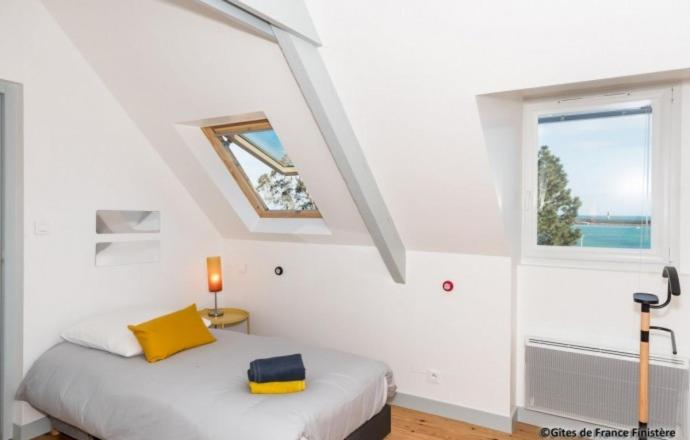 a bedroom with a bed with a yellow pillow and a window at Le Gîte du Port in Roscoff