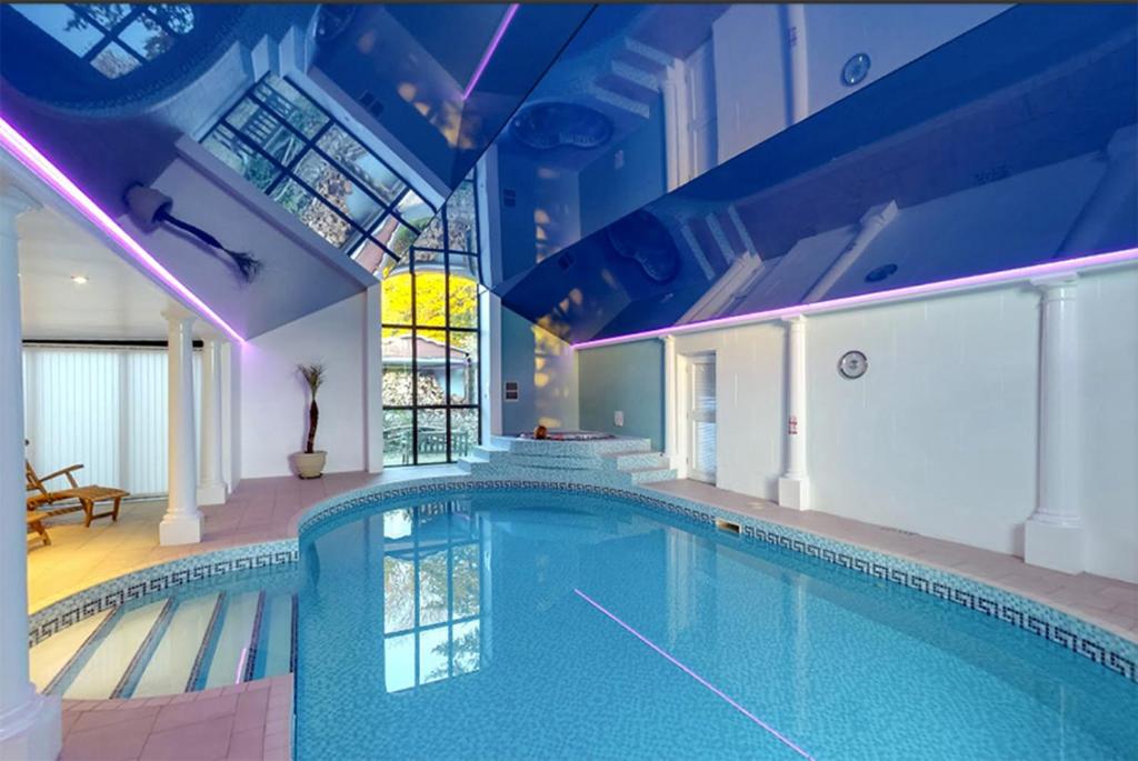 a swimming pool in a house with a blue ceiling at Berehayes Farmhouse in Bridport