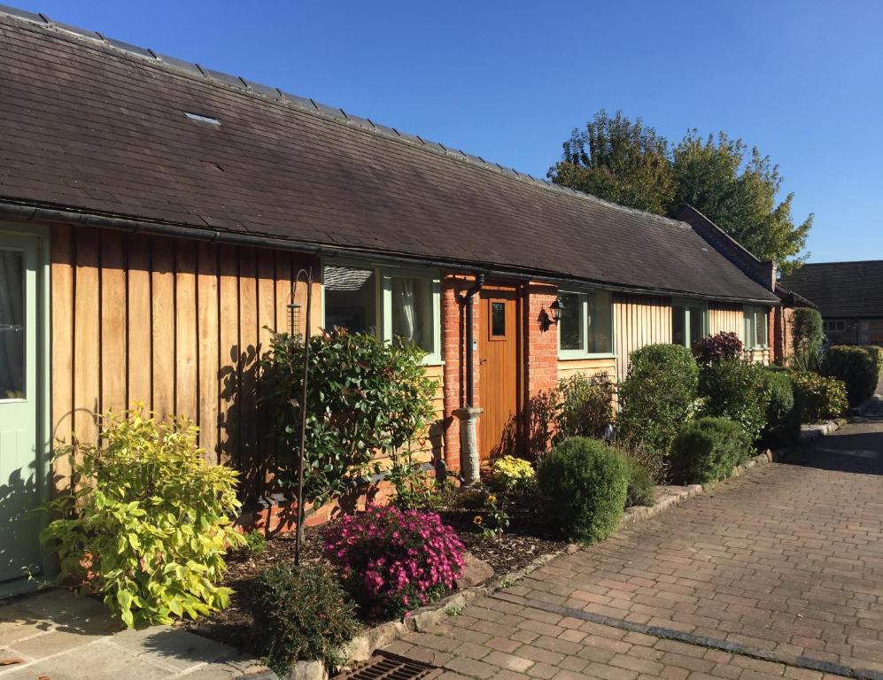 a row of cottages with bushes and flowers at Oak Barn in Wigginton