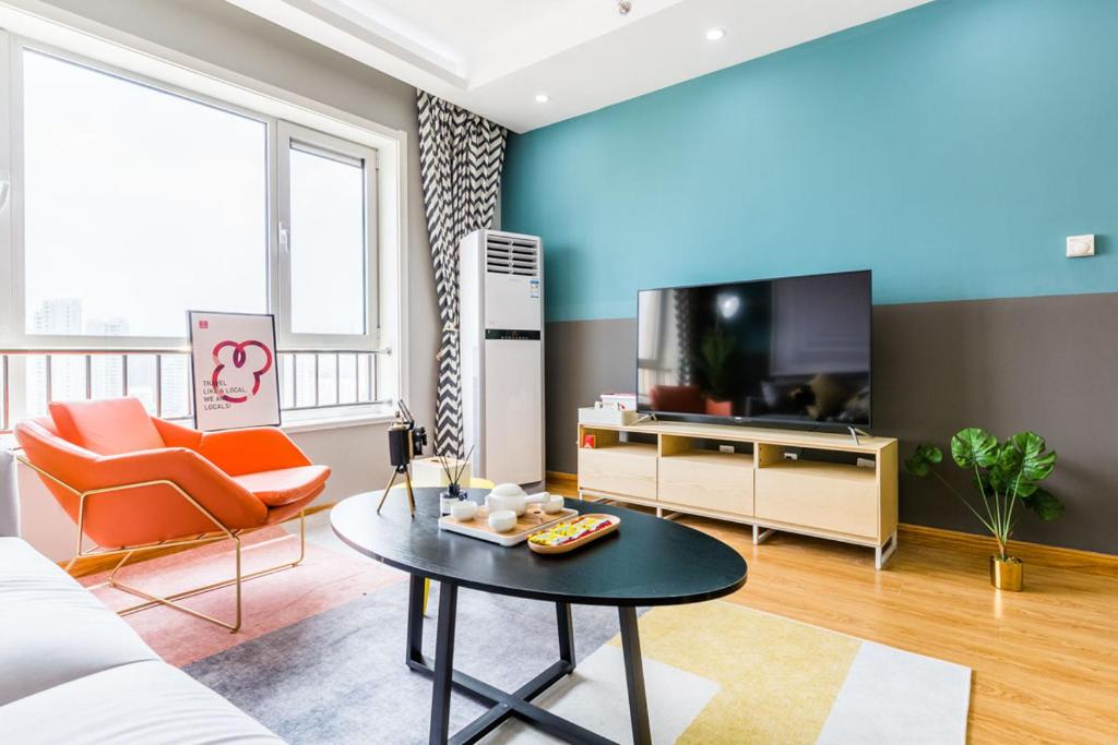 ein Wohnzimmer mit einem Sofa und einem TV in der Unterkunft Qingdao Shibei·Qingdao Wanda Plaza· Locals Apartment 00166560 in Qingdao