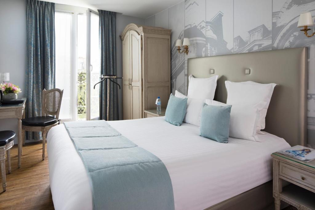 sypialnia z dużym białym łóżkiem z niebieskimi poduszkami w obiekcie Hotel Plaza Elysées w Paryżu