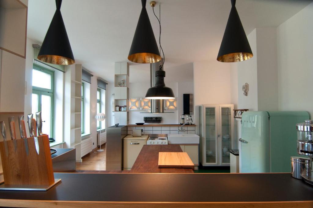 una cucina con tavolo in legno e lampadari a pendente neri di Sachsenperle a Dresda