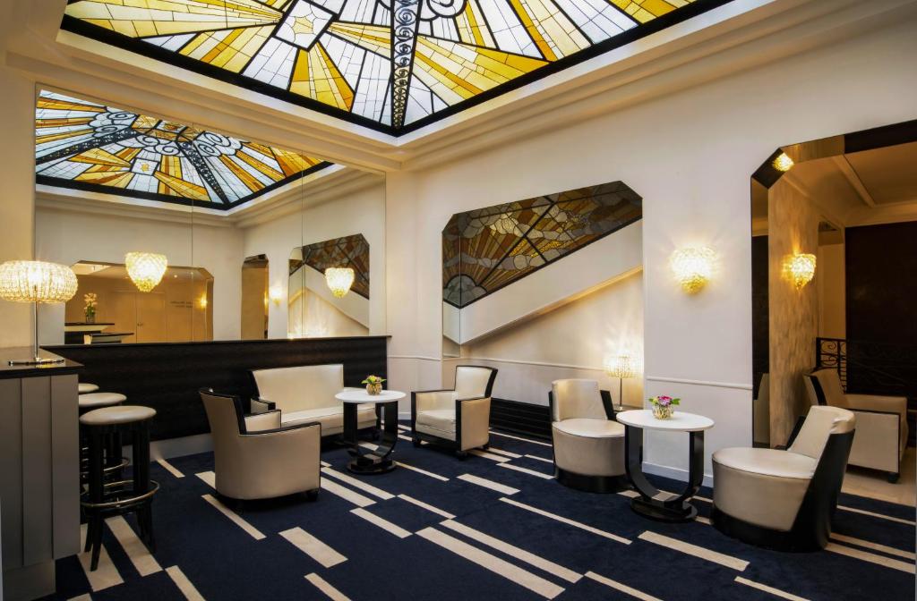 een lobby met een glas-in-loodplafond en tafels en stoelen bij Mercure Paris Opéra Faubourg Montmartre in Parijs