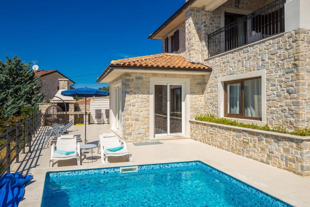 a villa with a swimming pool in front of a house at Villa Lurda Linardici Krk in Linardići