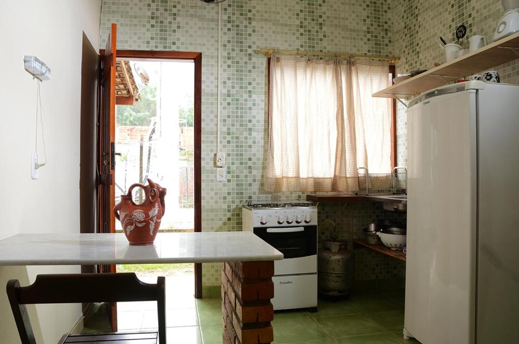 a kitchen with a table and a refrigerator at Trindade Hospeda - Estúdios e Casa Vila Trindade in Trindade