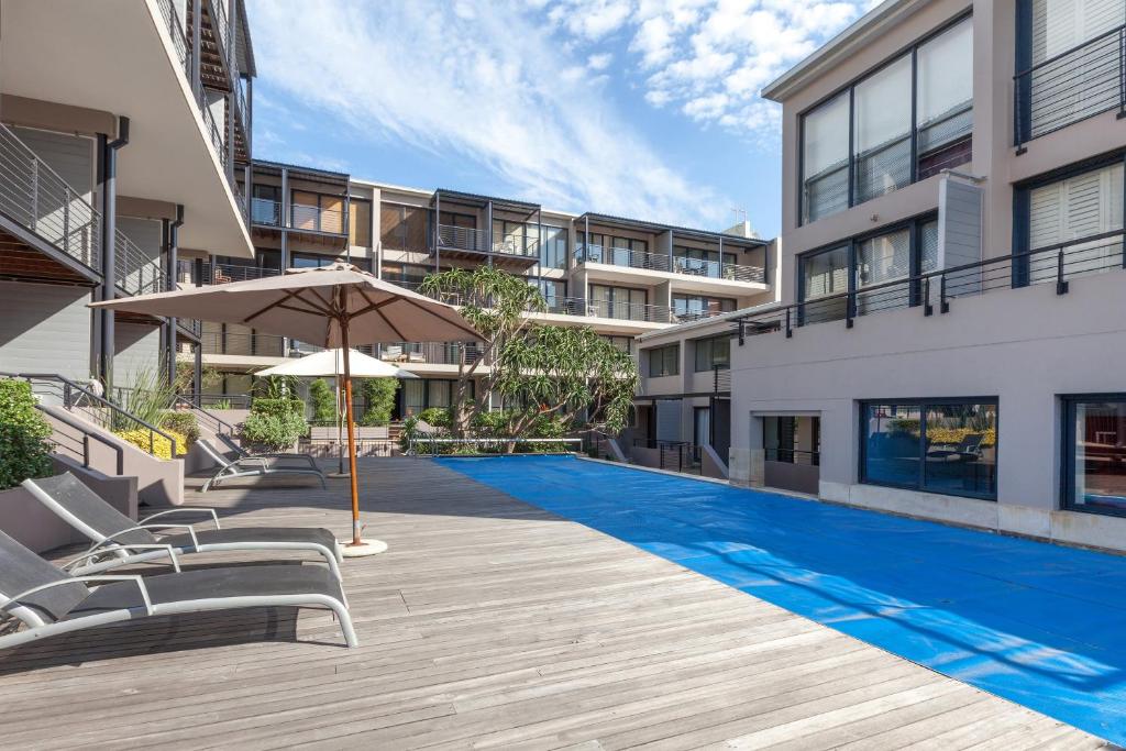 a swimming pool with chairs and an umbrella next to a building at Adderley Terraces J10 by CTHA in Cape Town