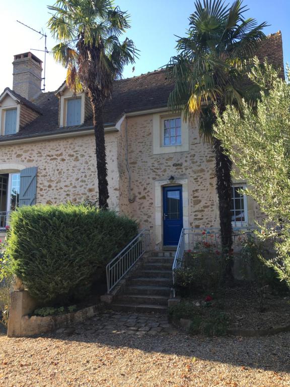 a house with a blue door and two palm trees at chambre privée in Lombron