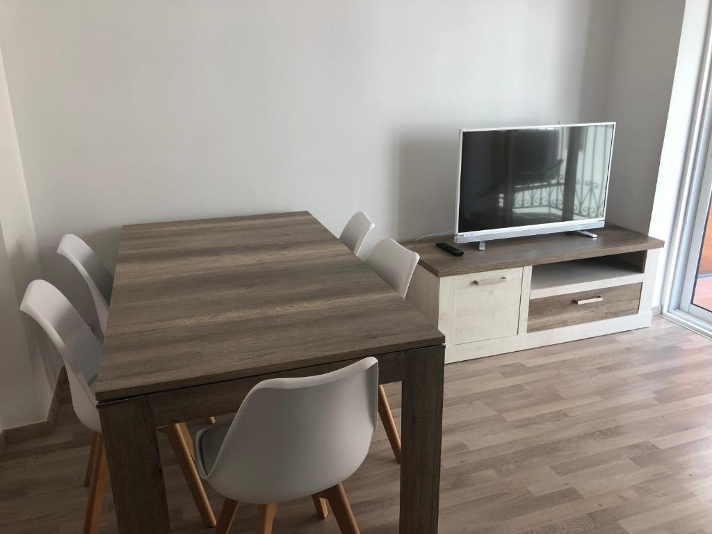 mesa de comedor con sillas blancas y TV en Apartamento Asuncion, en Benidorm