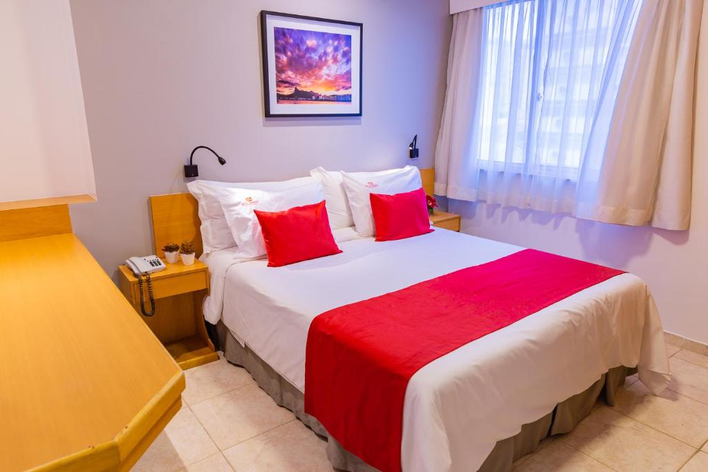 a hotel room with a large bed with red pillows at Hotel Vermont Ipanema in Rio de Janeiro