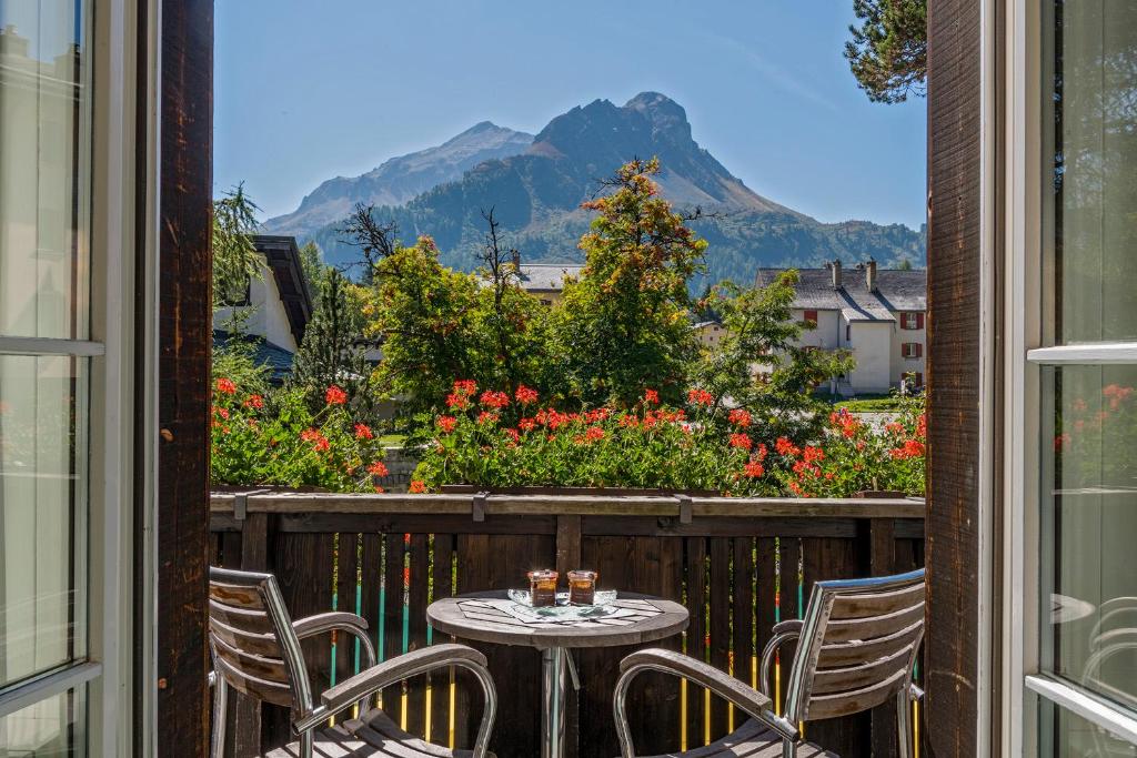 a table and chairs on a balcony with a view of a mountain at Schweizerhaus Swiss Quality Hotel in Maloja