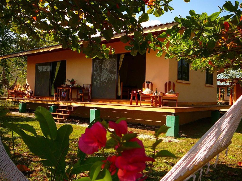 una casa con una terraza con sillas y una flor en Fidelito Ranch & Lodge en Tambor