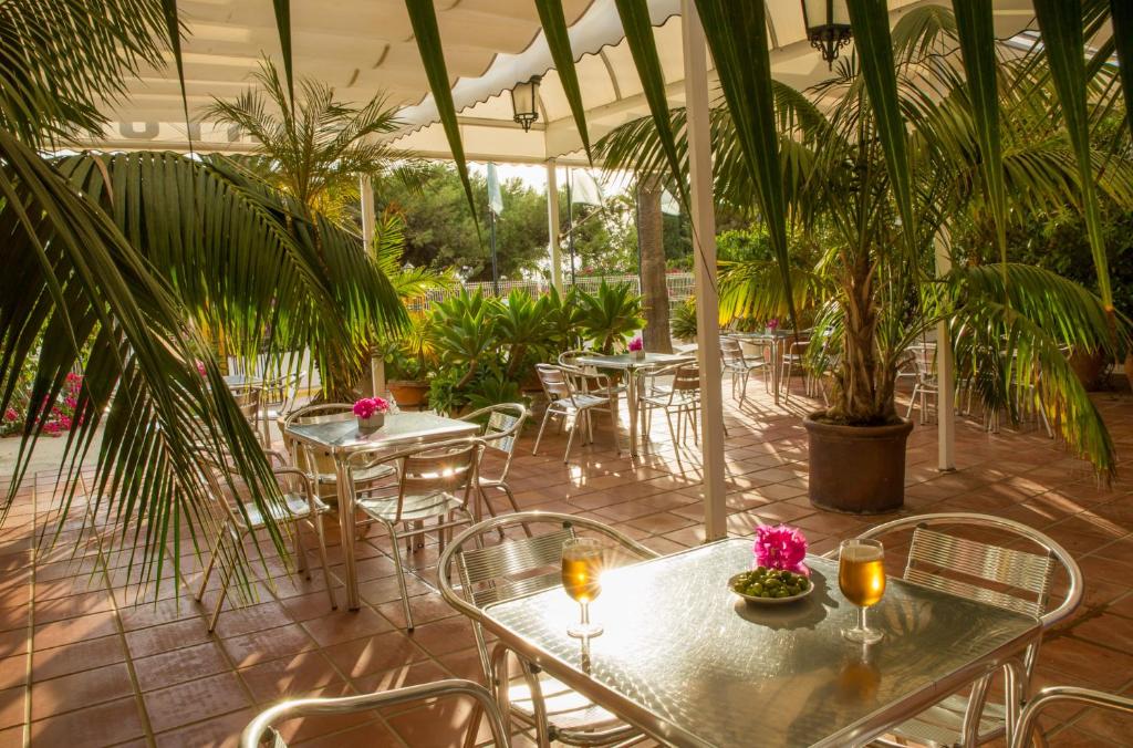 a patio with tables and chairs and palm trees at Fortuna in Los Caños de Meca