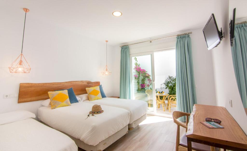 a bedroom with two beds and a table and a window at Fortuna in Los Caños de Meca
