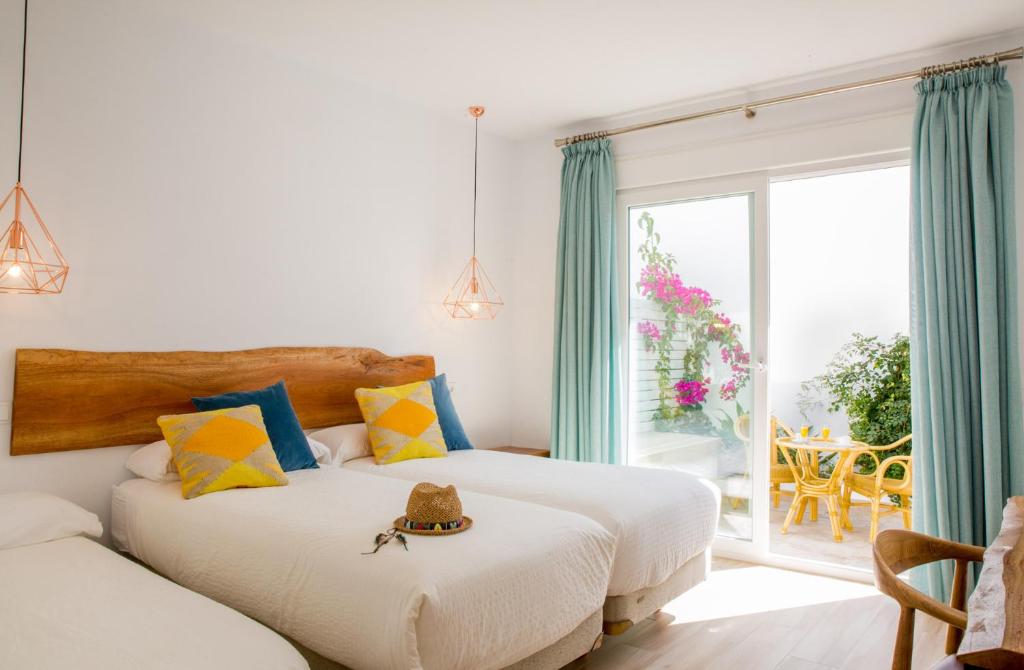 a bedroom with two beds and a window with a patio at Fortuna in Los Caños de Meca