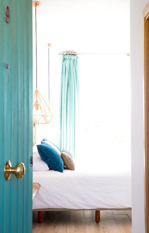 a bed with blue pillows in a bedroom with a window at Fortuna in Los Caños de Meca