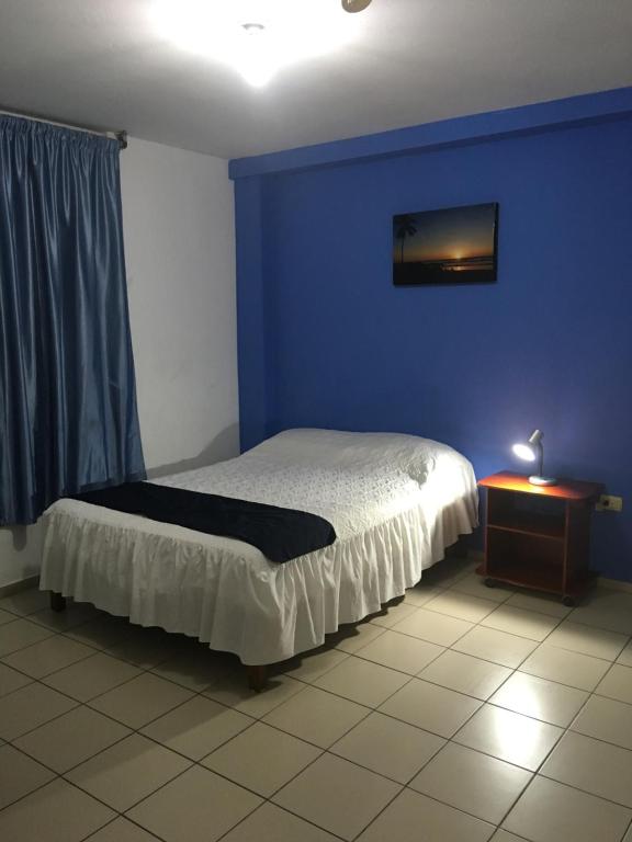 Un dormitorio con una cama con una pared azul y una mesa en Hostal Albatros, en Manta