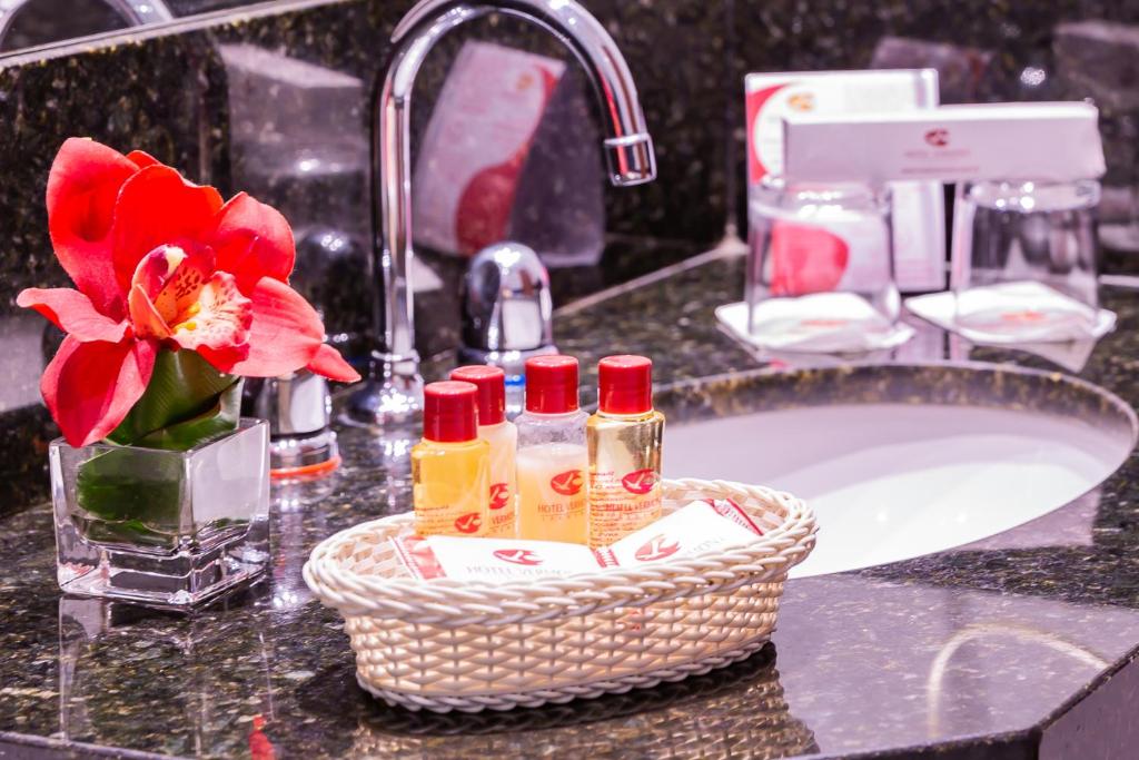 a bathroom sink with a basket of soap and a red flower at Hotel Vermont Ipanema in Rio de Janeiro