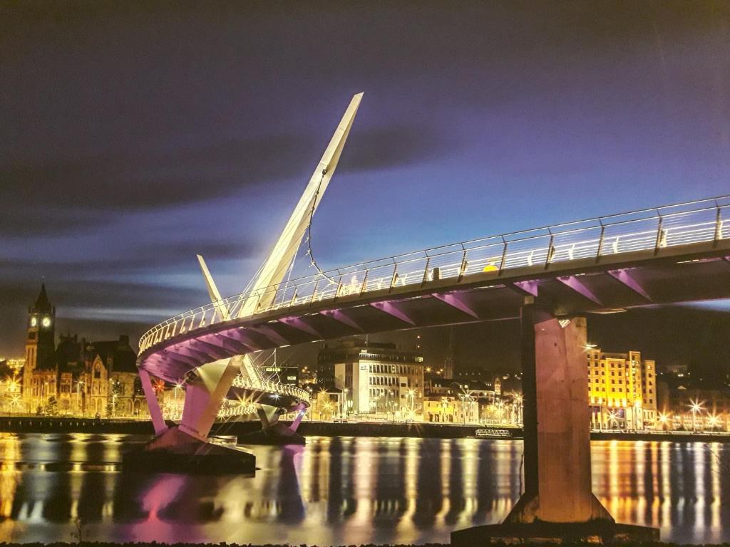 un pont sur l'eau avec une ville la nuit dans l'établissement Bridge House Derry City Townhouse Central free Parking, à Derry Londonderry