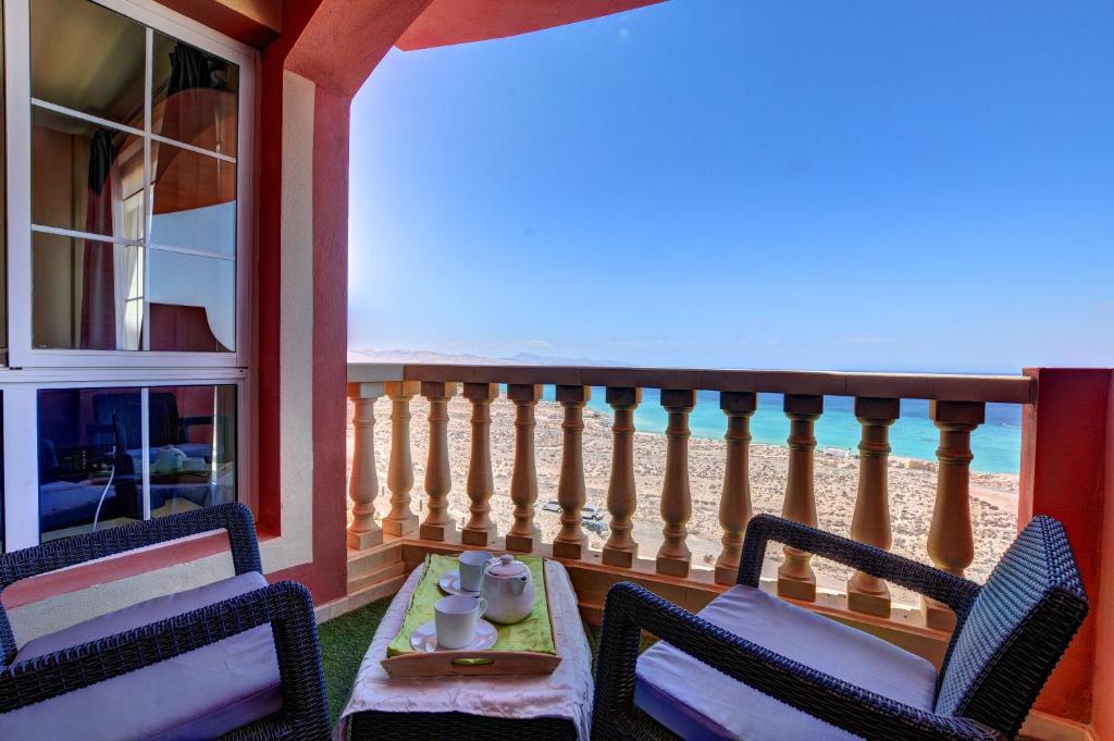 Un balcón con 2 sillas y una mesa con tazas y una mesa. en Amanecer Paraíso, en Costa Calma