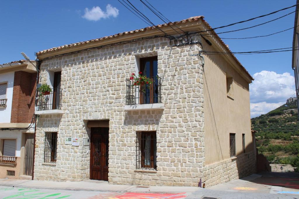 Casa Rural Los Montones في Carcelén: مبنى حجري وعلب ورد على النوافذ