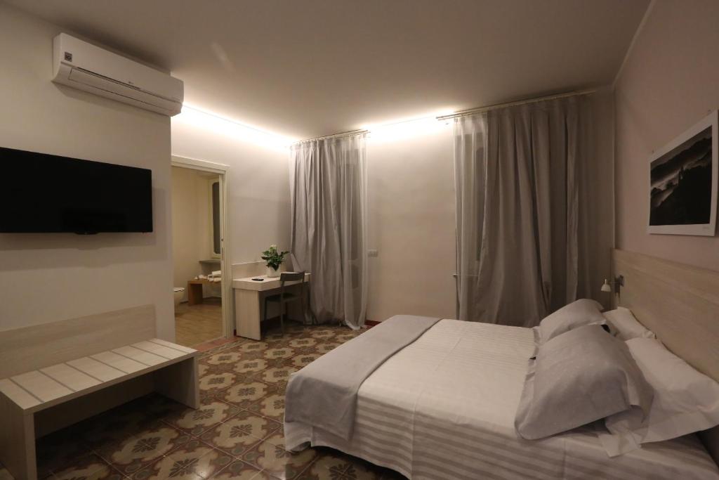 a hotel room with a bed and a flat screen tv at Palazzo Belli in Alba