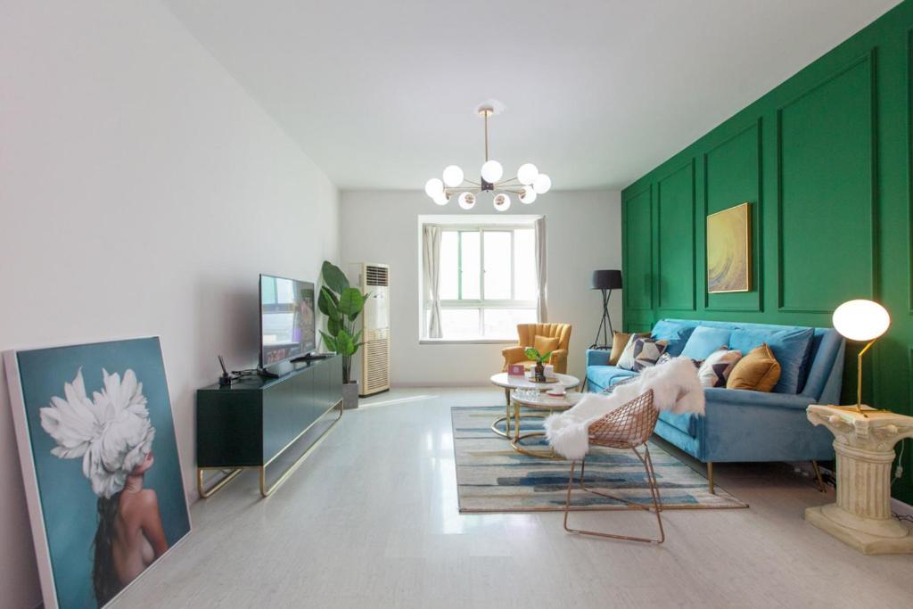 uma sala de estar com um sofá azul e uma parede verde em Wuhan Wuchang·Wuchang River Beach· Locals Apartment 00139250 em Wuhan