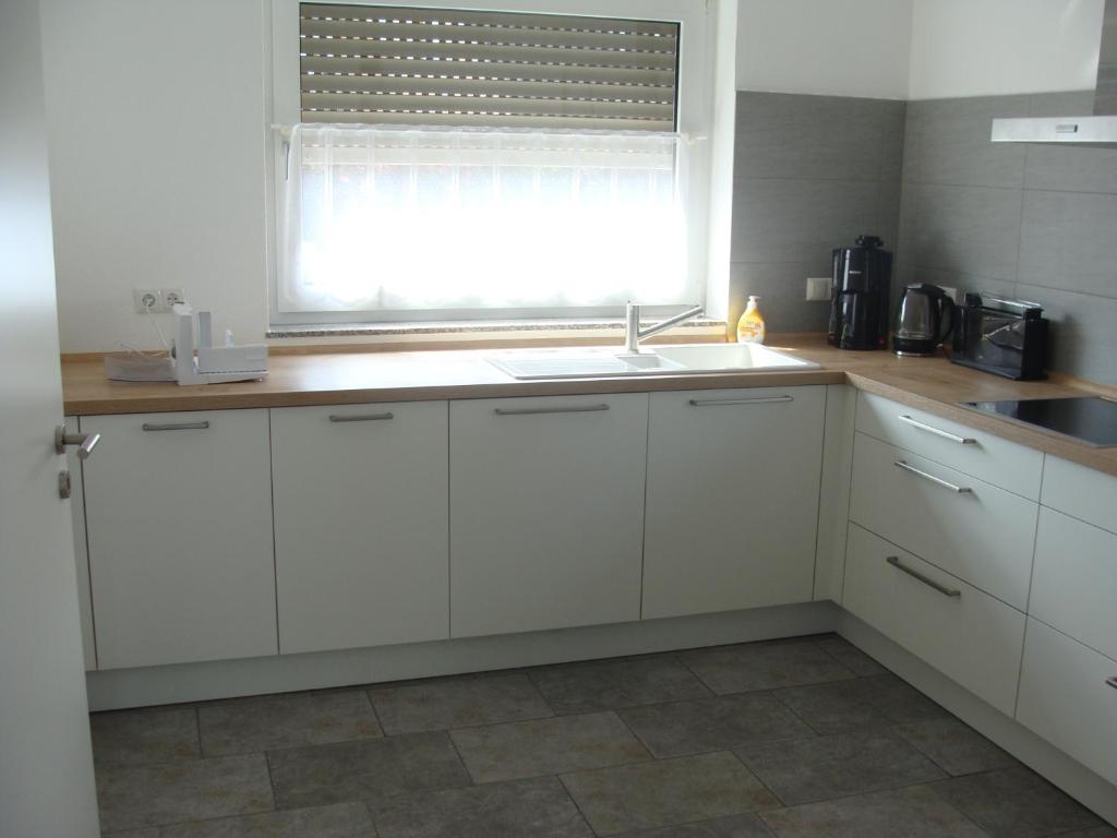 a kitchen with white cabinets and a sink and a window at Ferienhaus Landblick in Geldern