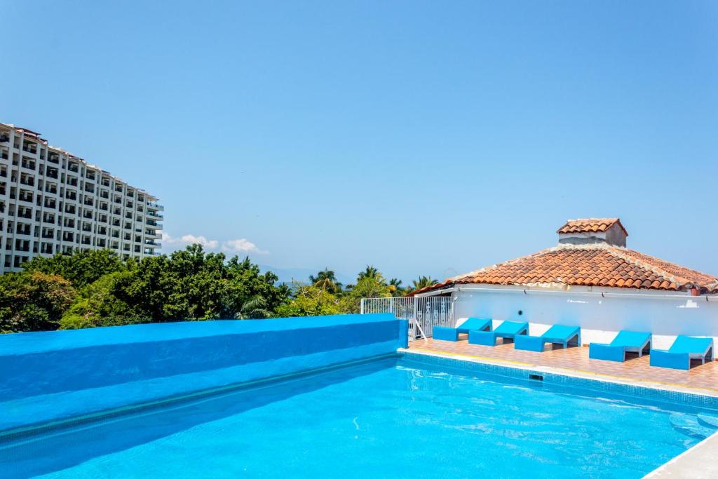 una piscina con sillas azules y un edificio en Hotel Encino Malecón Centro Puerto Vallarta en Puerto Vallarta