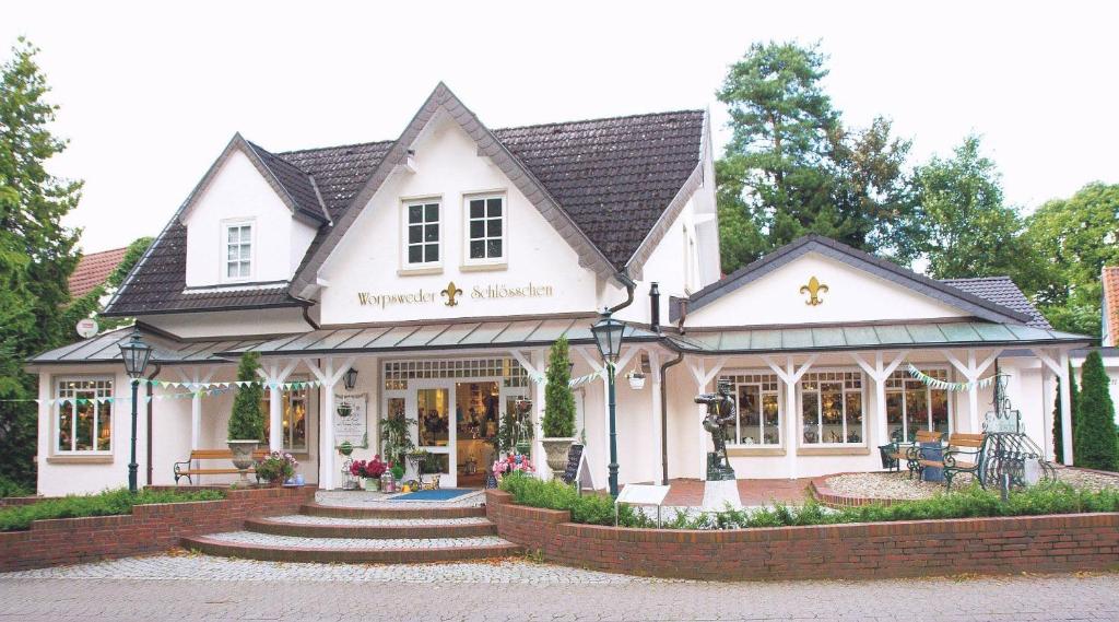 a white building with a store in front of it at Ferienwohnung Worpsweder Schlösschen in Worpswede