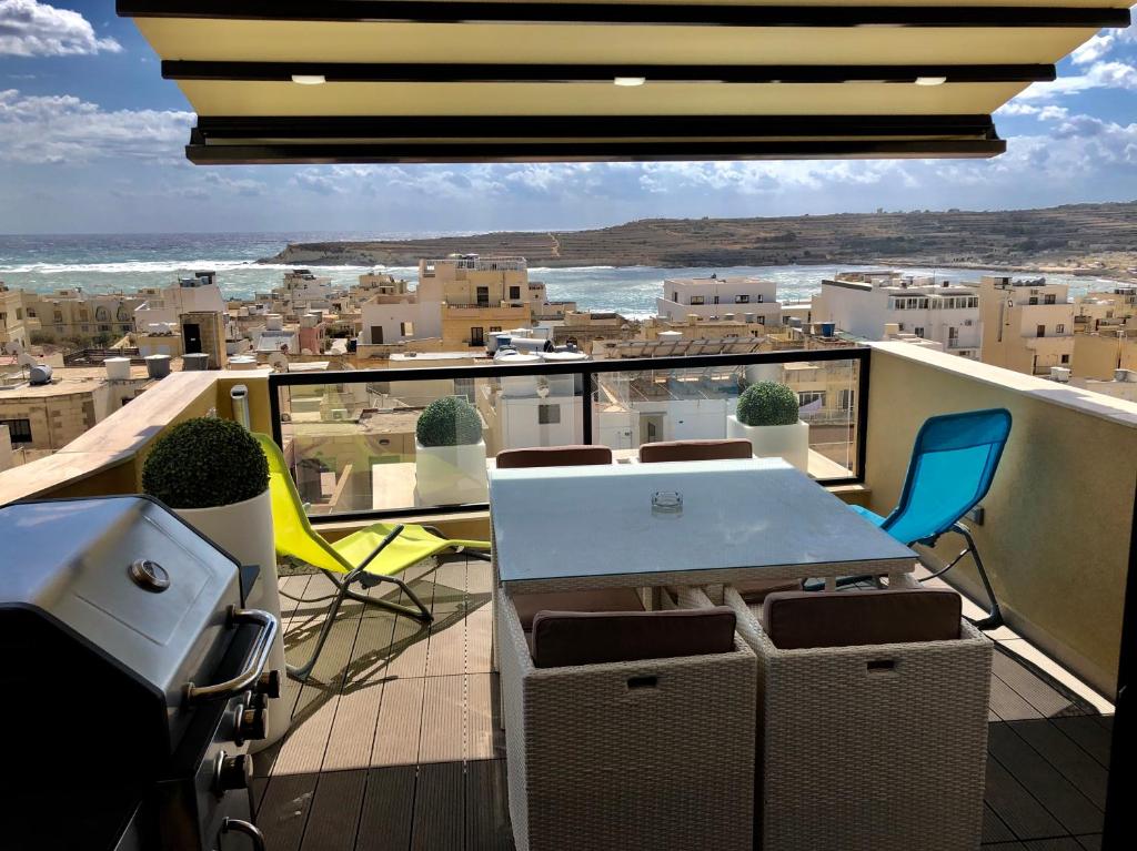 a balcony with a table and chairs and a view at Marsascala Sea View Apartment & Penthouse in Marsaskala