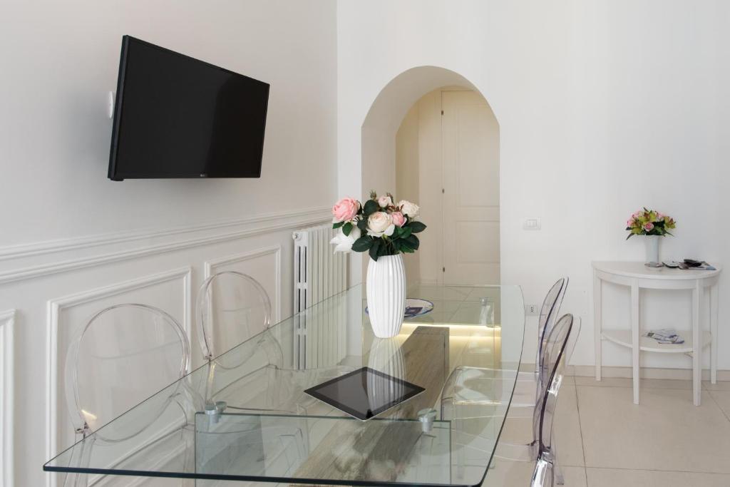 a glass table with a vase with flowers on it at Relais Mareluna - Luxury Apartments in Salerno