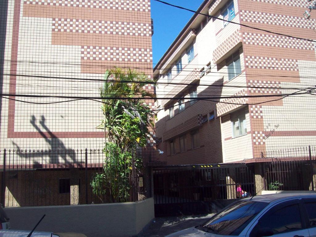 una calle con dos edificios altos y un coche en APARTAMENTO A 200 M DA PRAIA DO FORTE -PRÉDIO TRÊS RIOS, en Cabo Frío