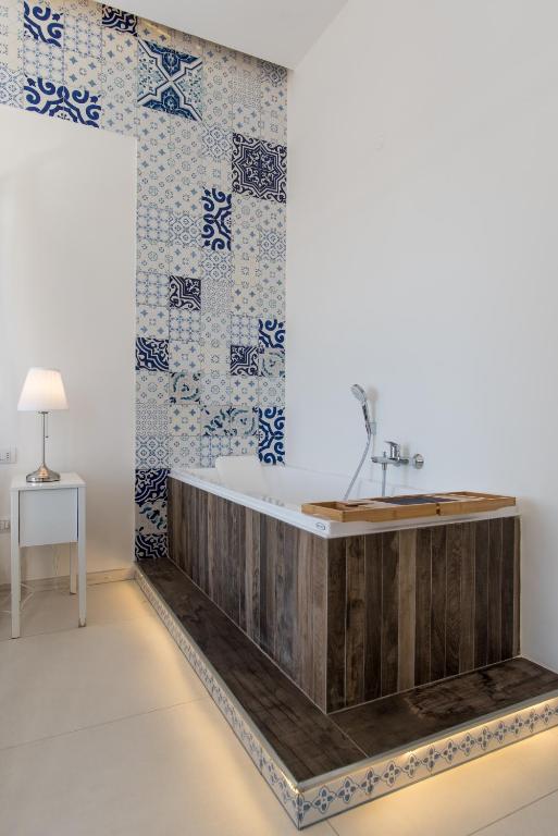 a bathroom with a wooden tub and blue and white tiles at Relais Mareluna - Luxury Apartments in Salerno
