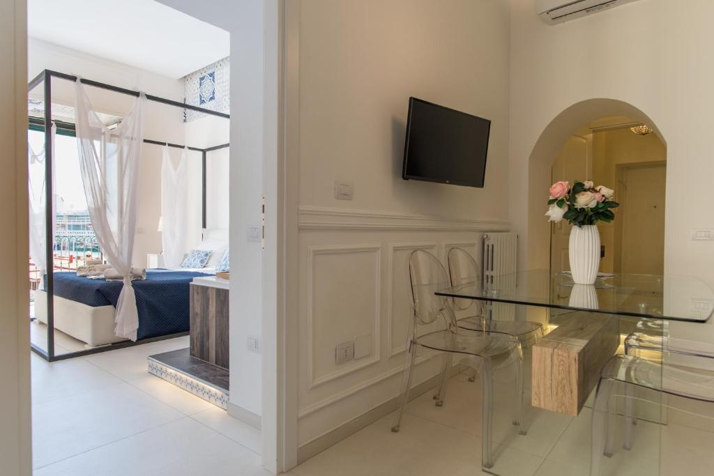 a dining room with a glass table and a tv at Relais Mareluna - Luxury Apartments in Salerno