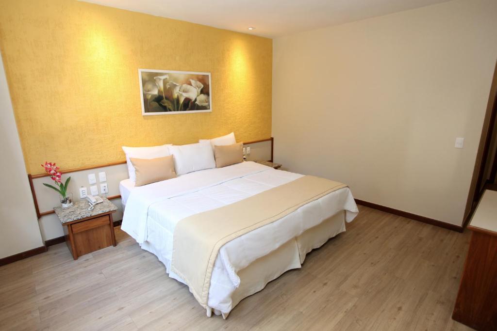 um quarto de hotel com uma grande cama branca em Mengo Palace Hotel no Rio de Janeiro