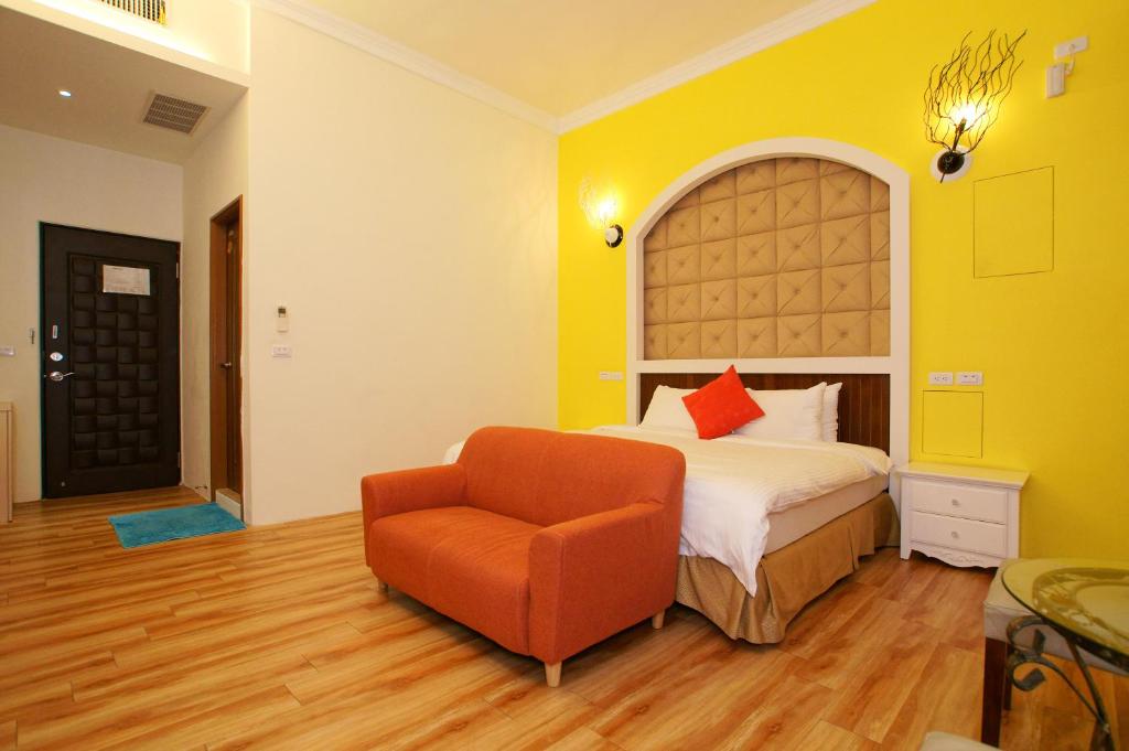 a bedroom with a bed and an orange chair at Taitung Venice B&B in Taitung City