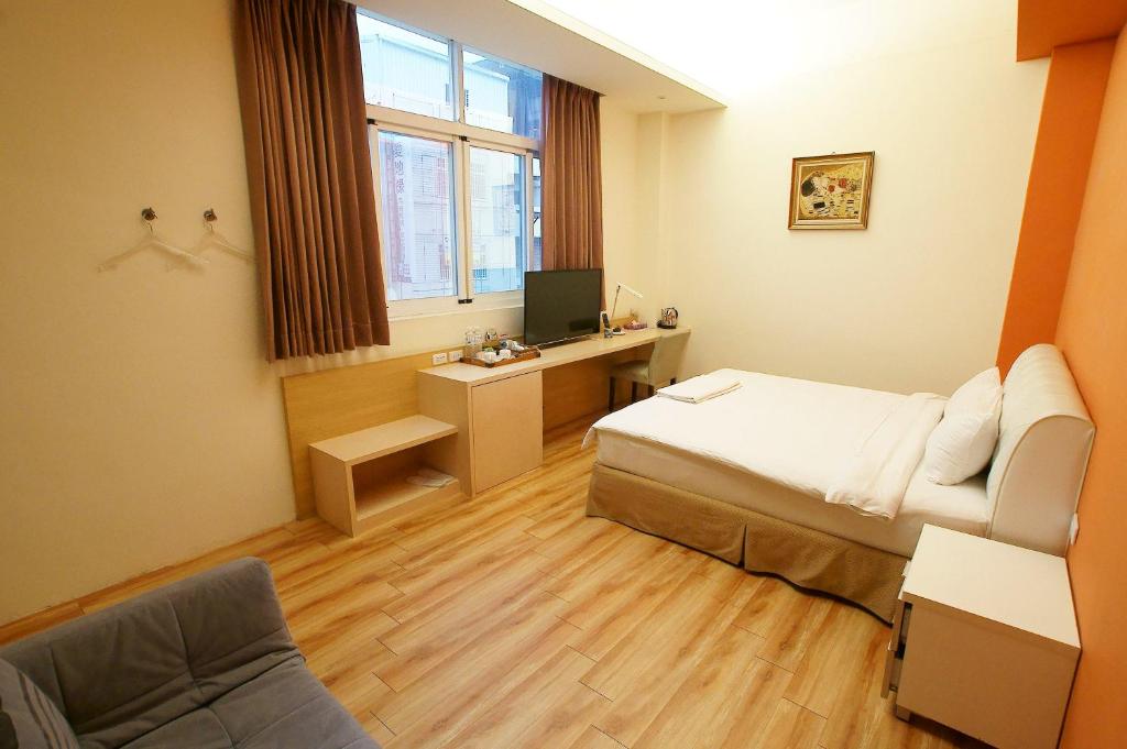 a bedroom with a bed and a desk with a television at Taitung Venice B&B in Taitung City