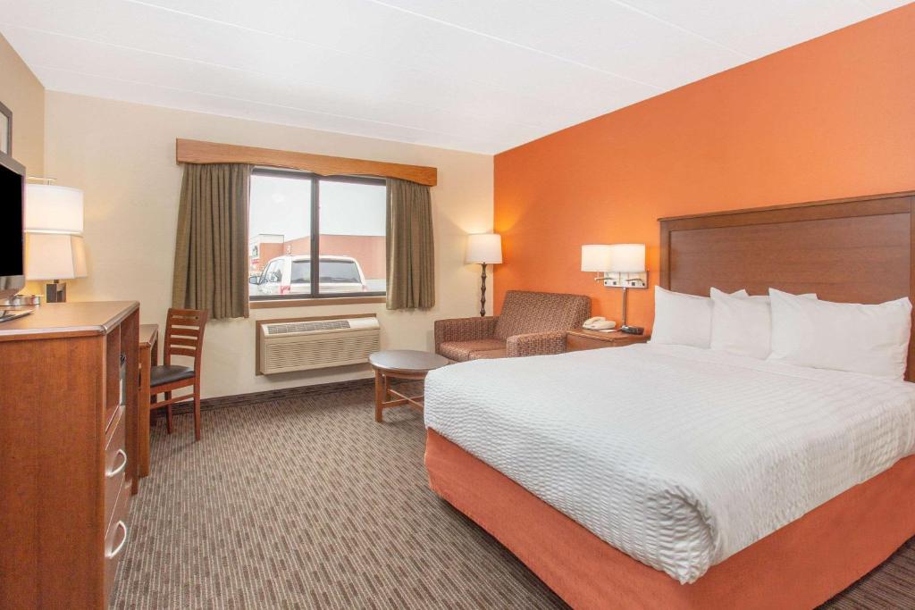 um quarto de hotel com uma cama, uma secretária e uma cadeira em AmericInn by Wyndham Calumet em Calumet