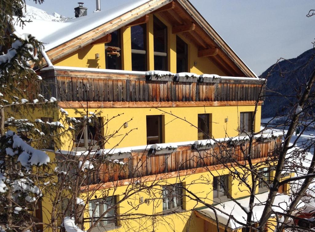 ein gelbes Gebäude mit Schnee auf dem Dach in der Unterkunft Haus Aperies in Pettneu am Arlberg