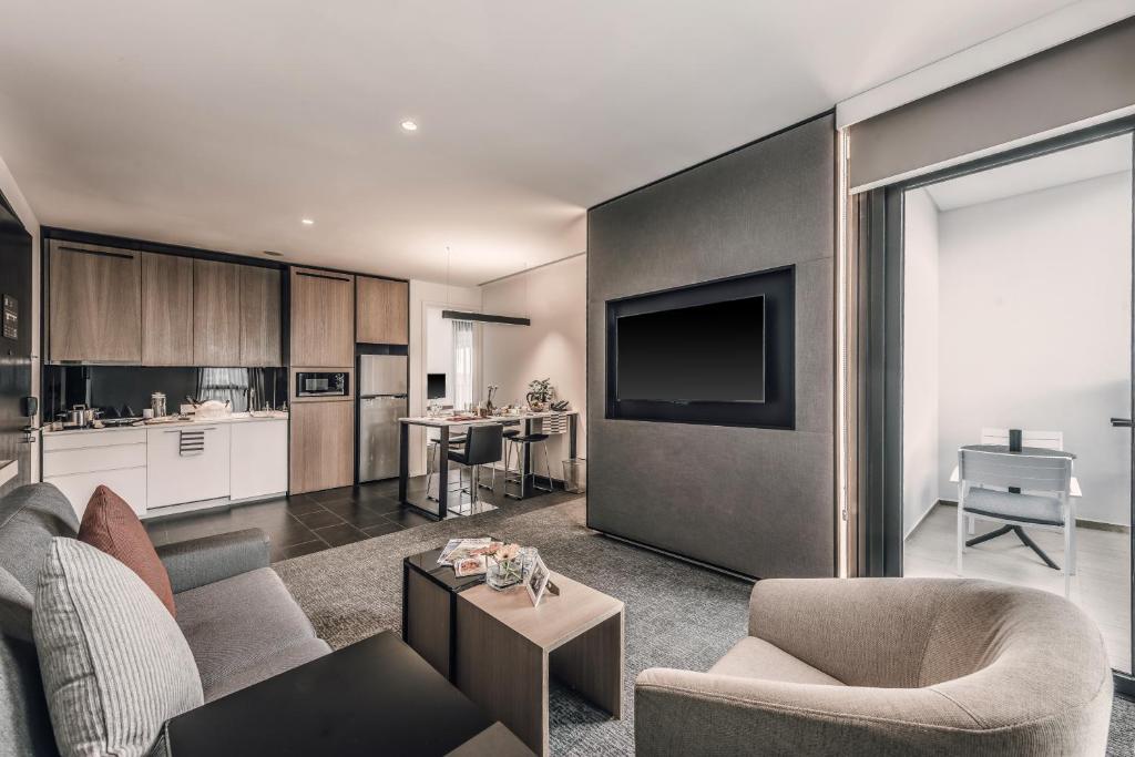 A suite living room with a compact kitchen and glass-door balcony or exterior space.