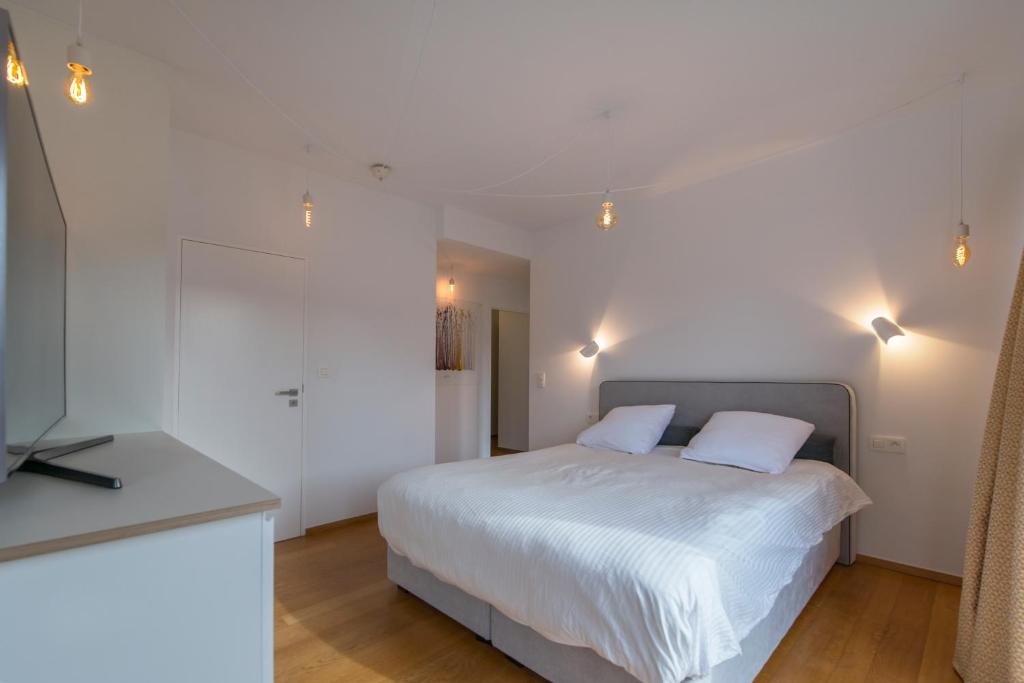 a bedroom with a white bed with two white pillows at Studio des jardins suspendus in Liège