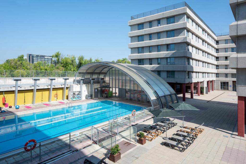 a swimming pool in front of a building at Madrid Airport Suites, Affiliated by Meliá in Madrid