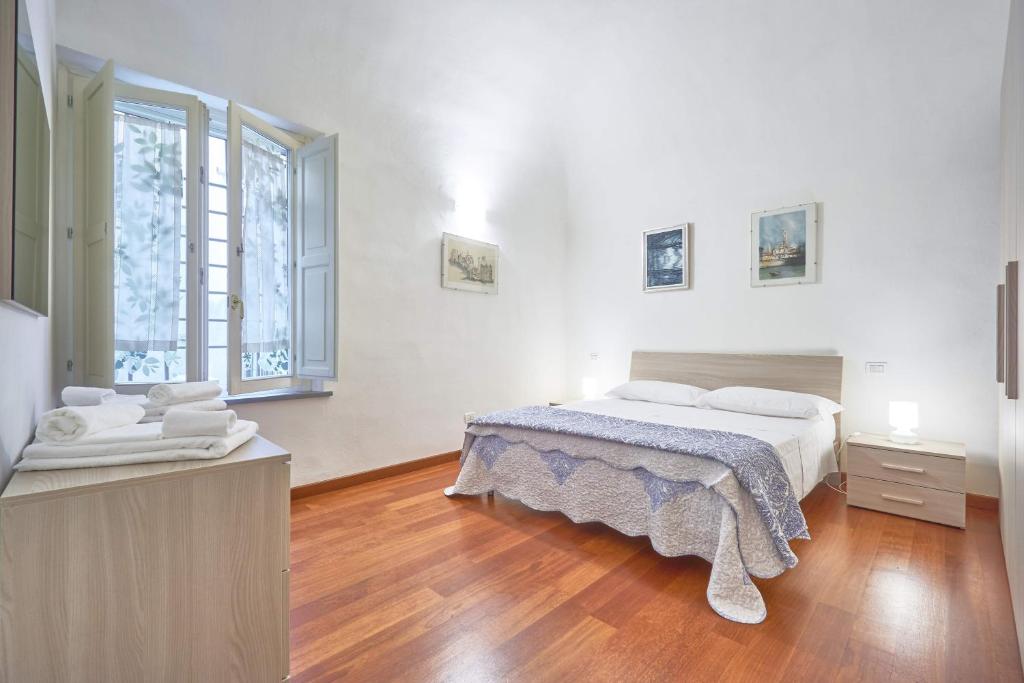 a white bedroom with a bed and a large window at Il Silenzioso in Pisa