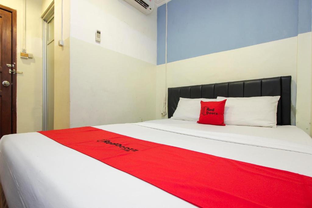 a bed with a red pillow on top of it at RedDoorz near Bethesda Manado in Manado