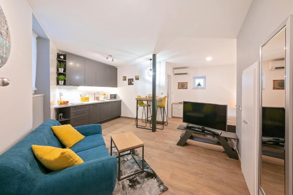 un salon avec un canapé bleu et une télévision dans l'établissement Mariva Downtown Studio, à Rovinj