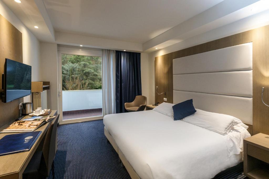 una camera d'albergo con un grande letto e una finestra di Hotel Terme Millepini a Montegrotto Terme