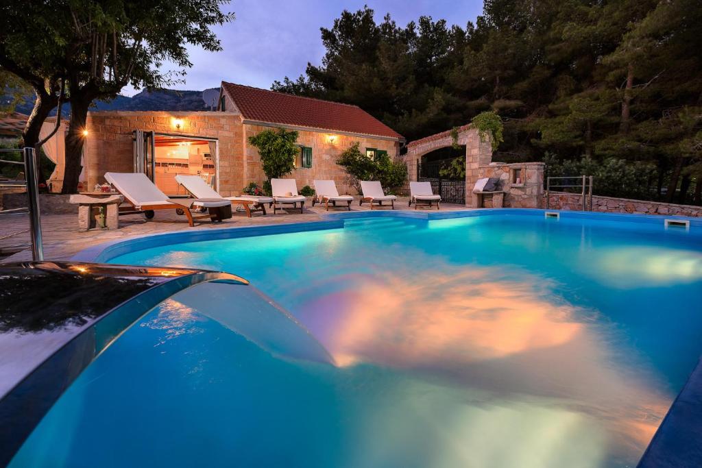 una piscina de agua azul frente a una casa en Villa Zlatni Rat with pool by the beach Zlatni rat in Bol - Brac en Bol