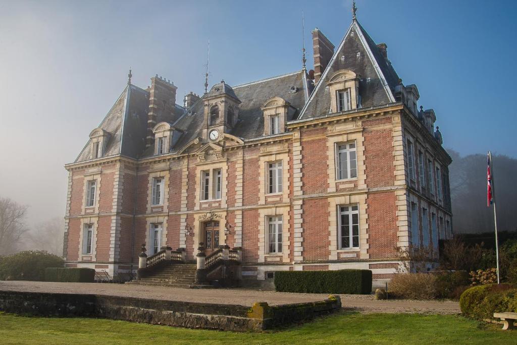 a large red brick building with a clock on it at Golf Hotel in Saint-Saëns