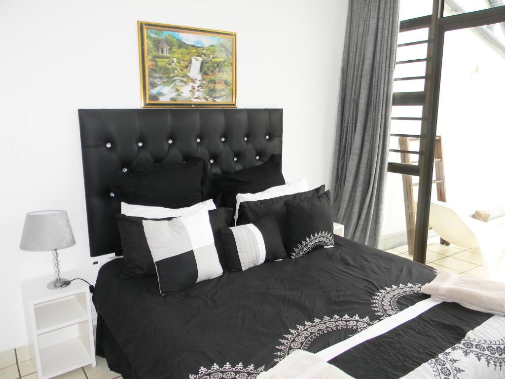 1 dormitorio con cama negra y almohadas blancas y negras en Dumela Margate Flat No 14, en Margate